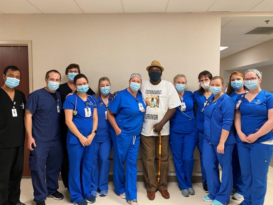 Man wearing a Coronavirus Survivor t-shirt standing with his hospital care team. 