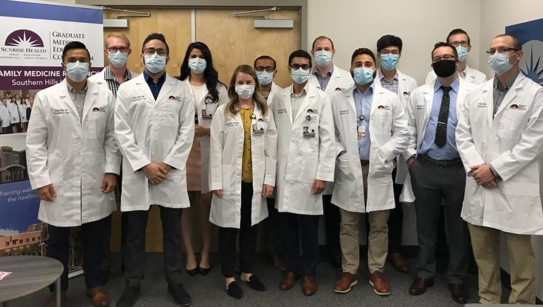 Group of resident physicians wearing white lab coats and face masks. 