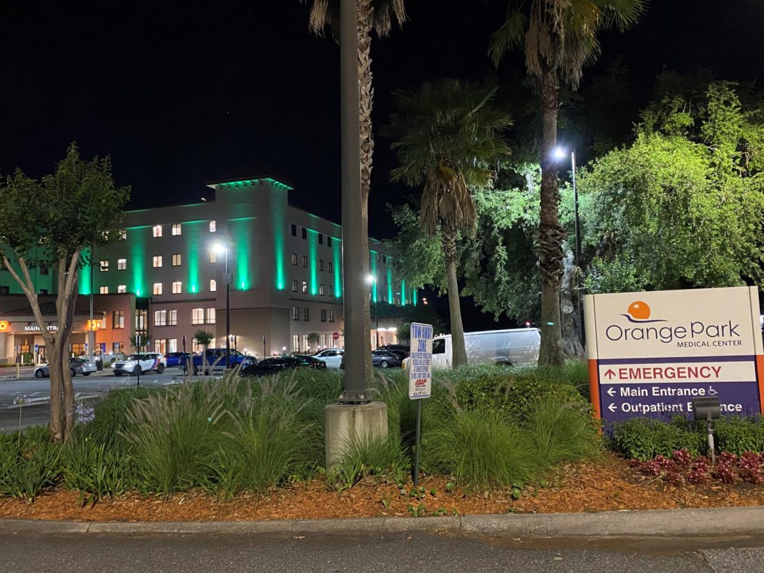Exterior view of a hospital lit with green lights. 