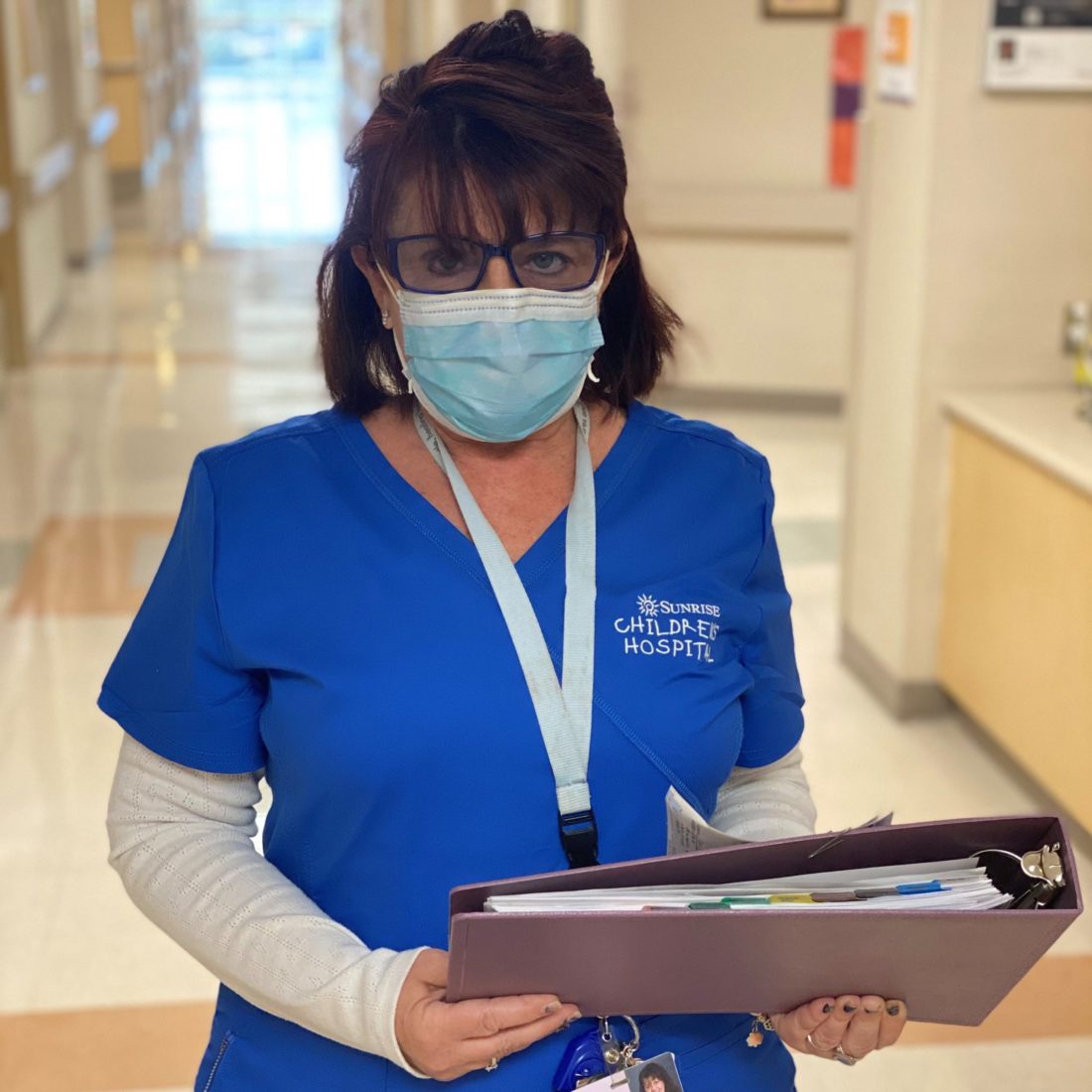 A female nurse wearing scrubs and a face mask. 