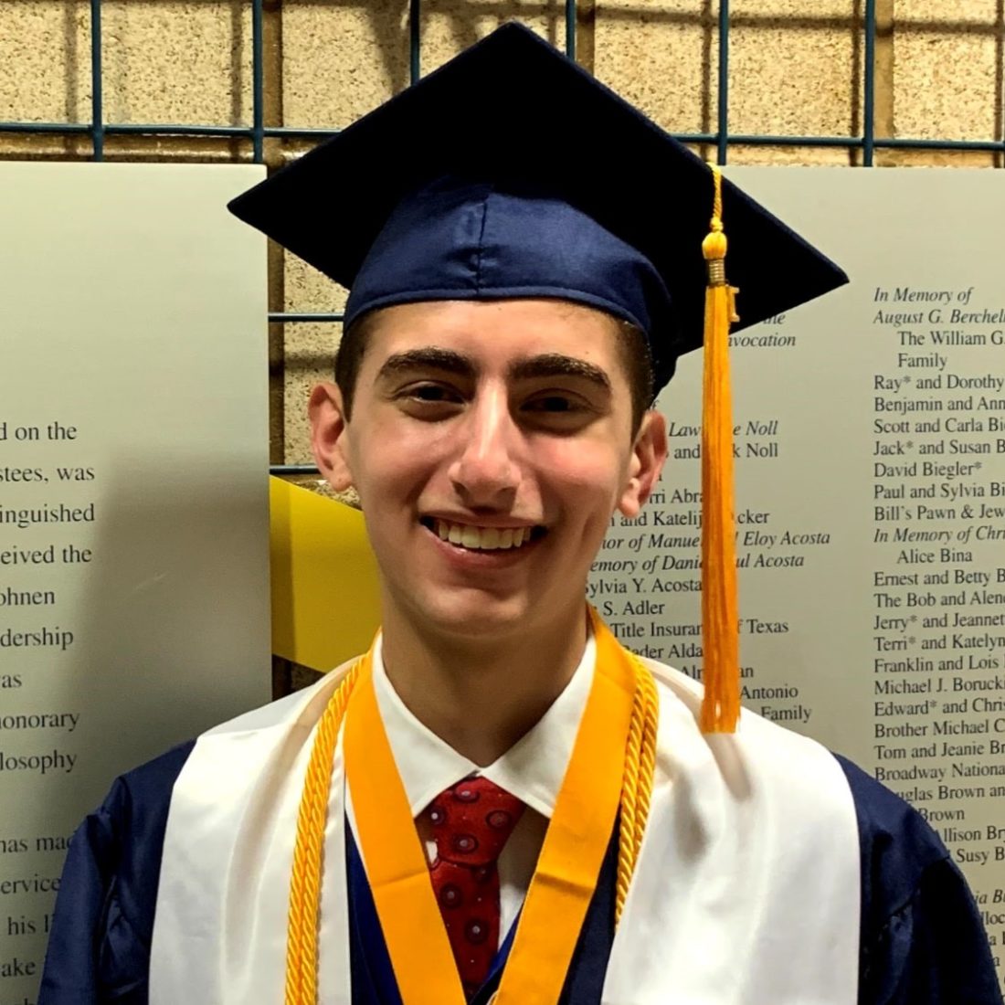 young male in graduate cap and gown who is a scholarship recipient