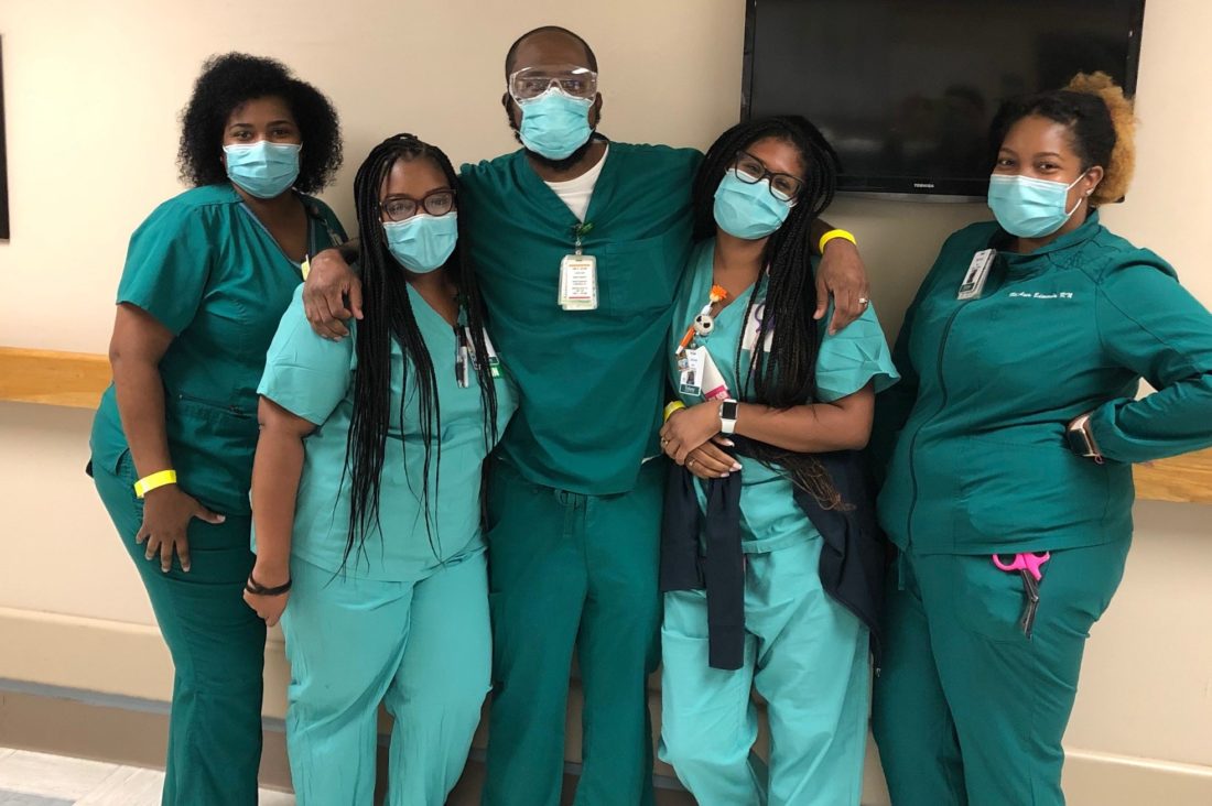 Five hospital caregivers wearing scrubs and face masks. 