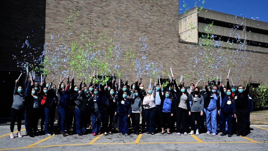 People standing outside a hospital with confetti poppers to celebration national transplant milestone. 