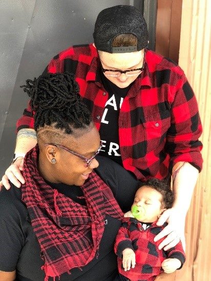 Kadesha holding a baby with her spouse. 