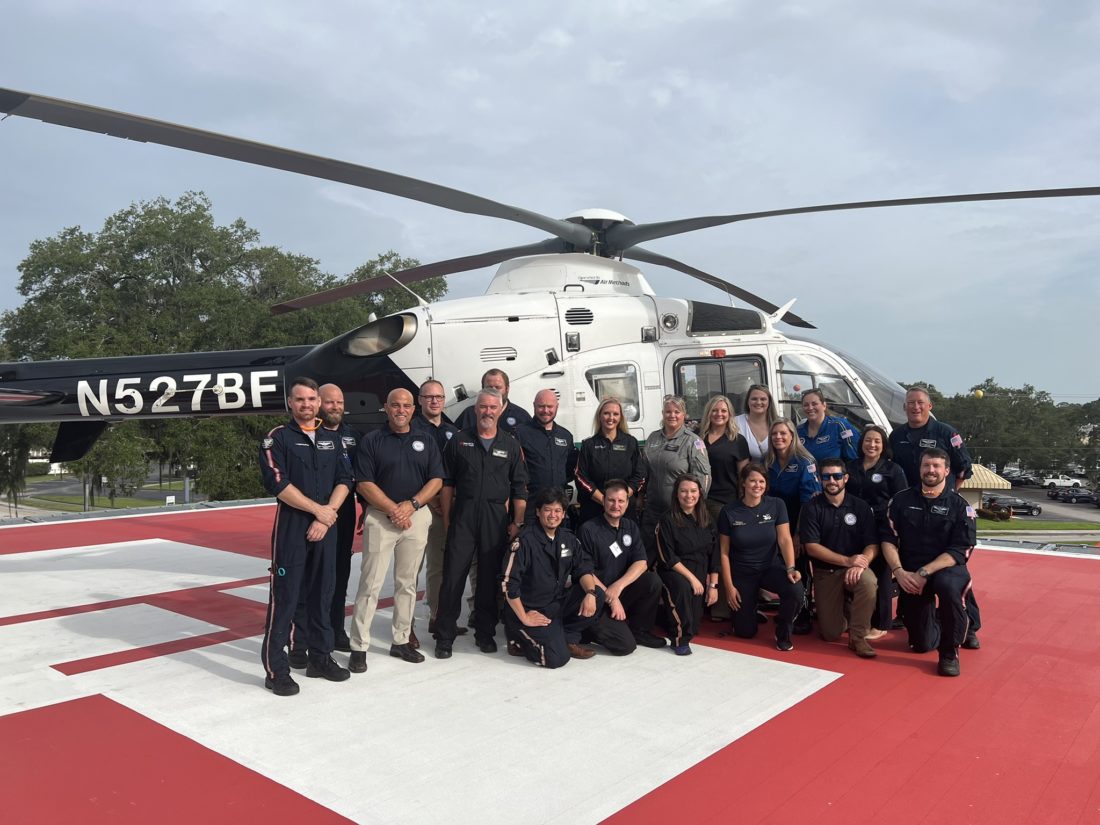 HCA Healthcare's NICU Incident Response Team smiling for photo on helipad in front of helicopter. 