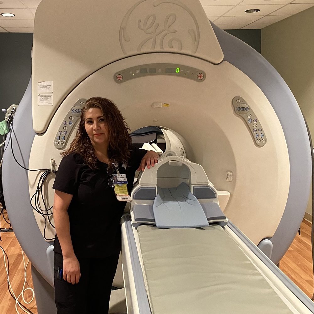 Lourdes Zamora standing next to a MRI machine 