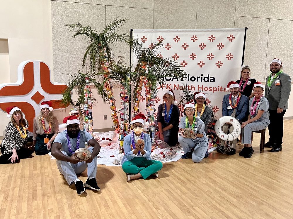 HCA Healthcare colleagues sitting around canned goods organized in the shape of palm trees.