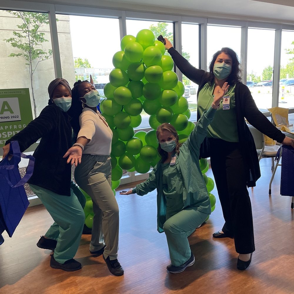 Four HCA Healthcare Mission Hospital colleagues standing by green balloons in the shape on an "A." 