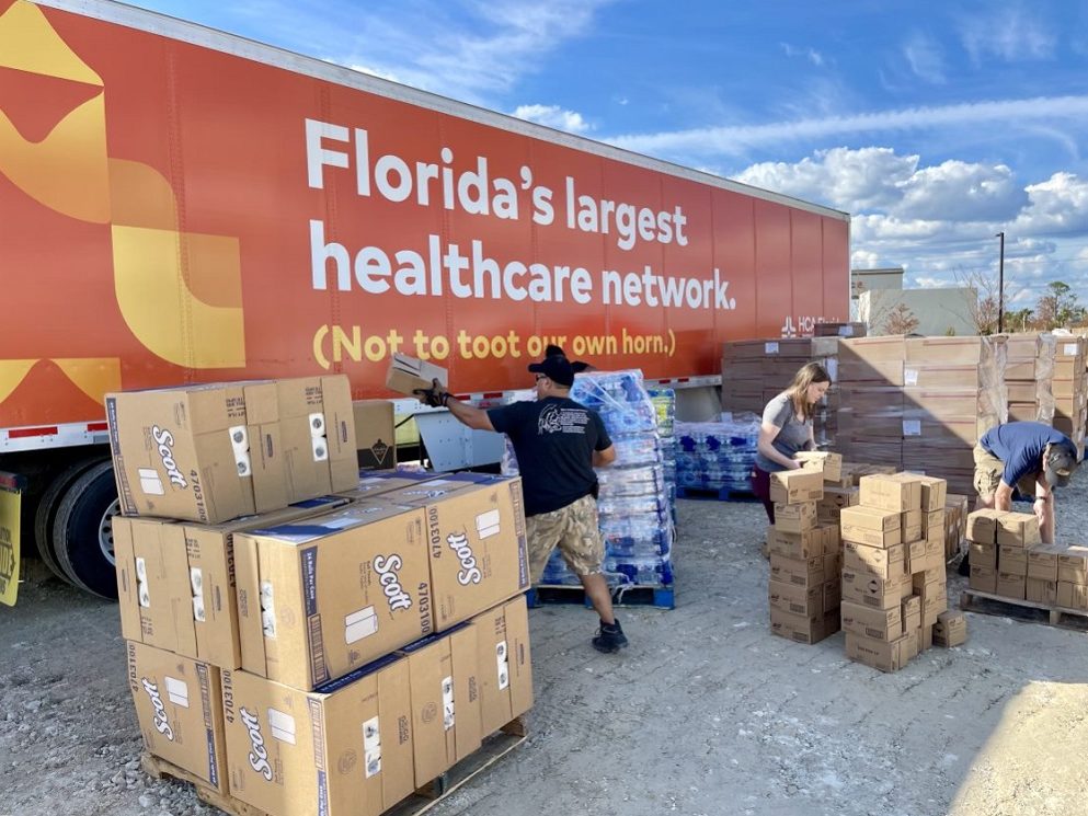 Truck with "Florida's largest healthcare network" written on it parked near boxes of supplies. 