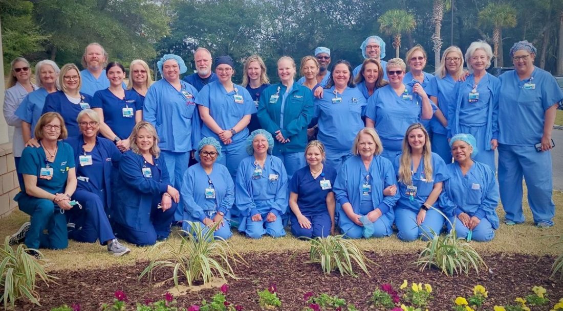 HCA Florida Twin Cities Hospital colleagues wearing scrubs smile for picture in garden. 