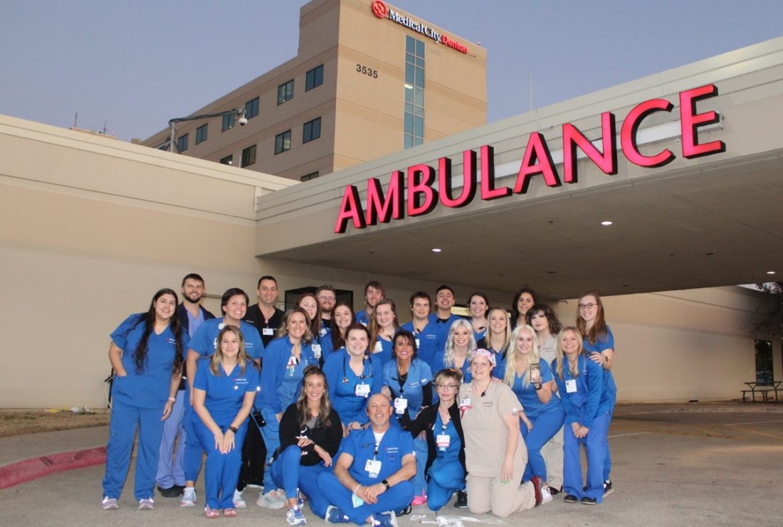 HCA Healthcare colleagues in scrubs standing outside an ambulance bay at a Medical City Denton.