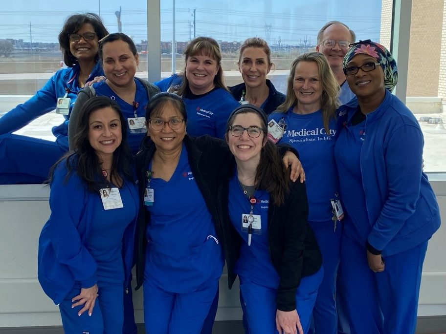 Medical City Frisco colleagues in scrubs smile for group picture. 
