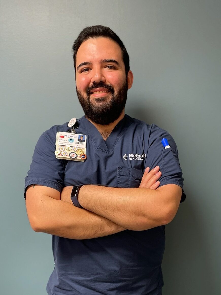 Andrew Delgado wearing scrubs standing in a hospital. 