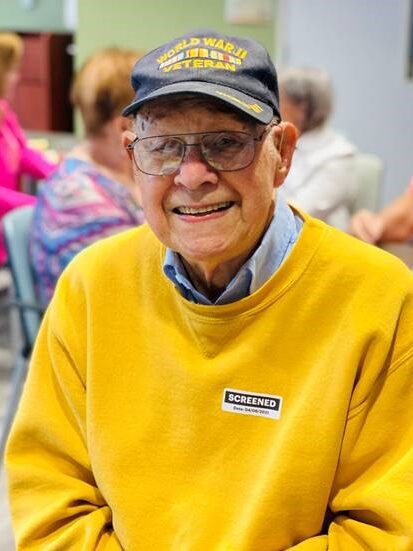 100-year-old hospital volunteer in an orange jacket and a veteran hat