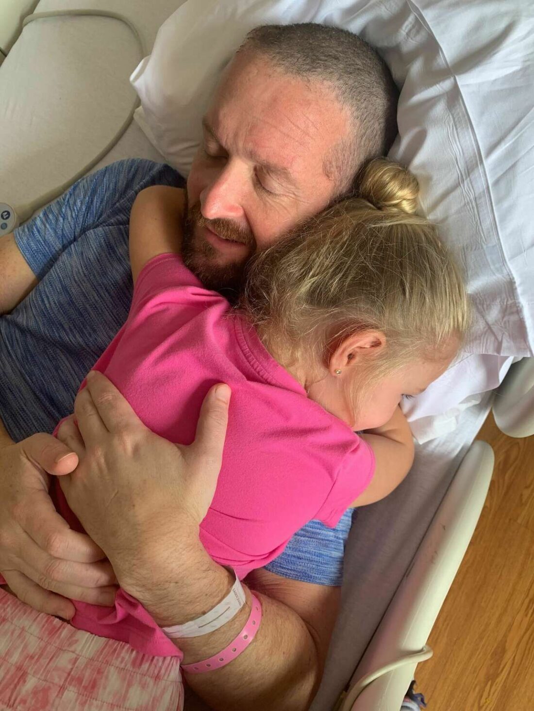 Father hugs his daughter in a hospital bed 
