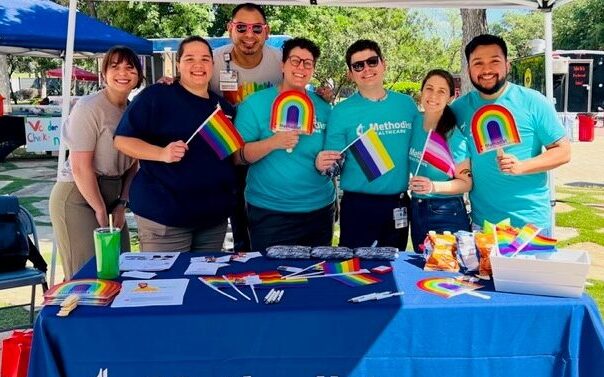HCA Healthcare colleagues holding Pride flags at a table