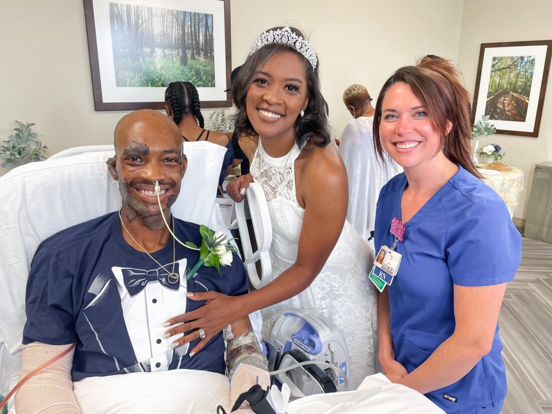 HCA Healthcare burn patient and his new wife smile for a picture with a member of his care team. 