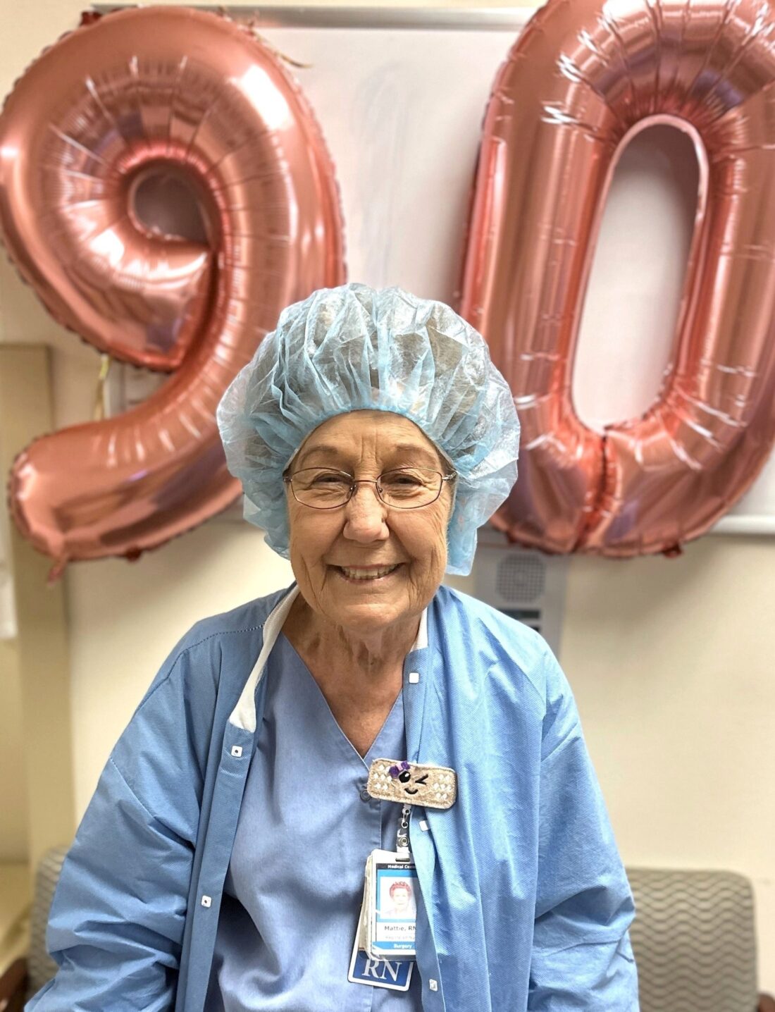 HCA Healthcare nurse Ms. Mattie in front of balloons that read "90"